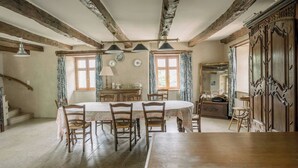 A dining area with a wooden table and chairs, a chandelier, and a staircase.