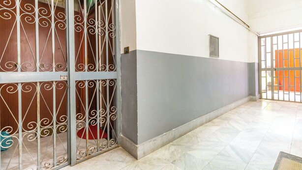 A hallway with a metal gate, a tiled floor, and a wall with a grey and white color scheme.