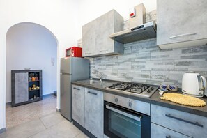 A modern kitchen with grey cabinets, a built-in stove, and a tiled backsplash.