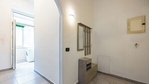 A hallway with a washing machine in the background, a vanity with a mirror and a cabinet, and a radiator on the wall.