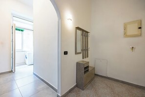 Um corredor com uma máquina de lavar no fundo, uma toucador com espelho e armário, e um radiador na parede.