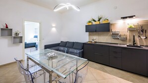 A modern kitchen with a glass dining table, dark cabinets, and a built-in oven.