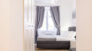 A bedroom with a bed, a bedside table, and a window with curtains.