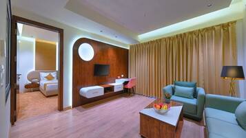A hotel room with a bed, a desk, a sofa, a coffee table, and a TV.