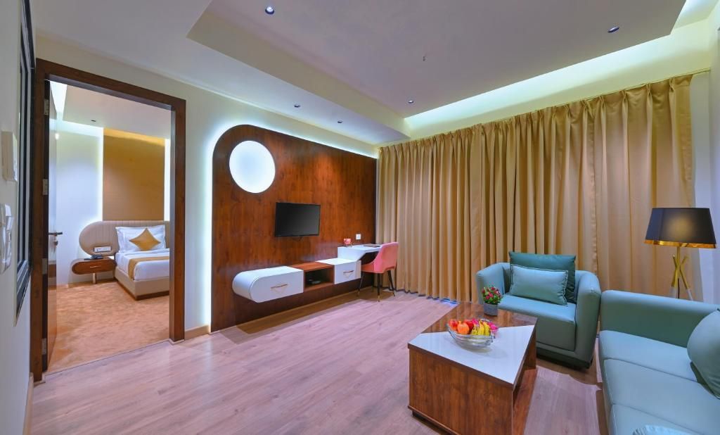 Una habitación de hotel con una cama, un escritorio, un sofá, una mesa de centro y una televisión.