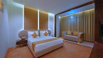 Una habitación de hotel moderna con una cama grande, un sofá, una mesita de noche y una televisión.