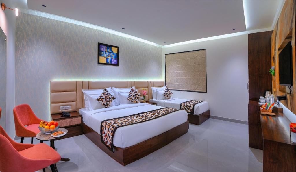 A modern hotel room with two beds, a small seating area, and a desk with a mirror.