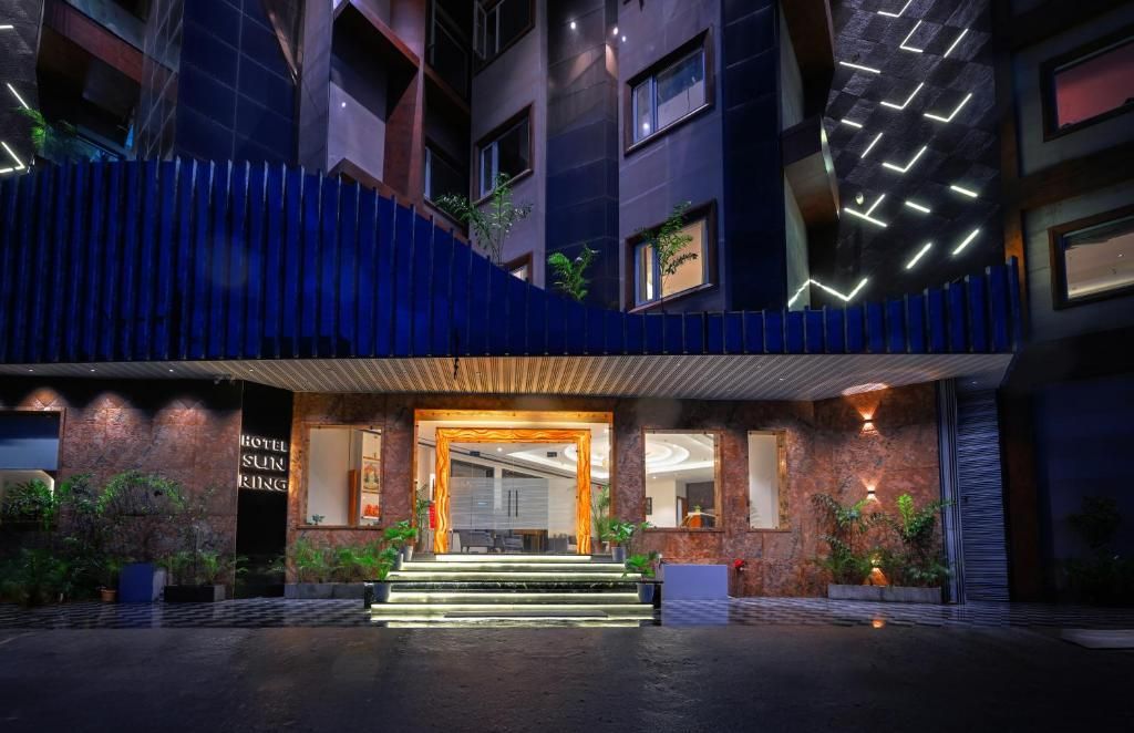 Een hotelentree met een modern ontwerp, met een opvallende ingang, treden die naar de deur leiden en een bord met de naam van het hotel.