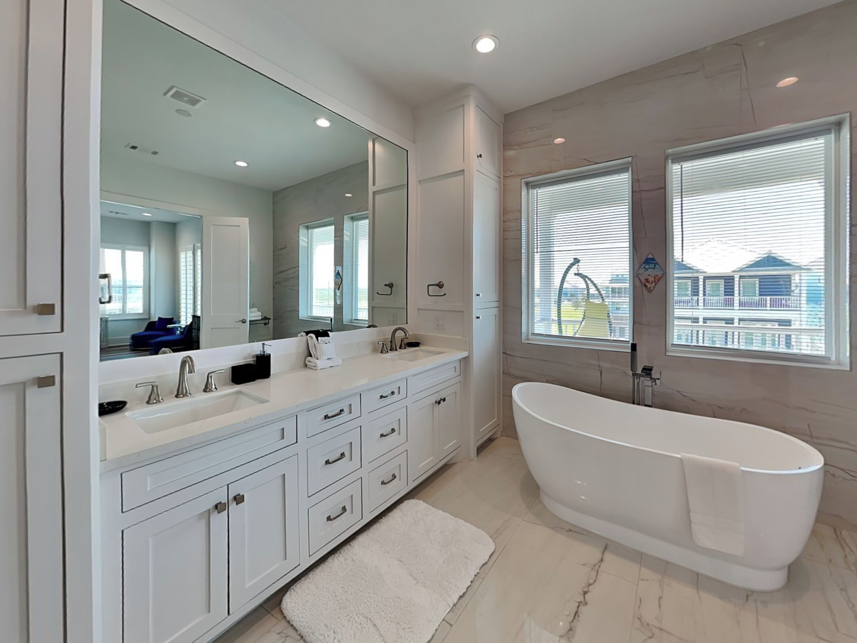 A modern bathroom with a large freestanding bathtub, a double sink vanity, and a large mirror.