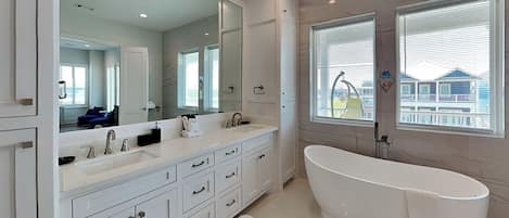 A modern bathroom with a large freestanding bathtub, a double sink vanity, and a large mirror.
