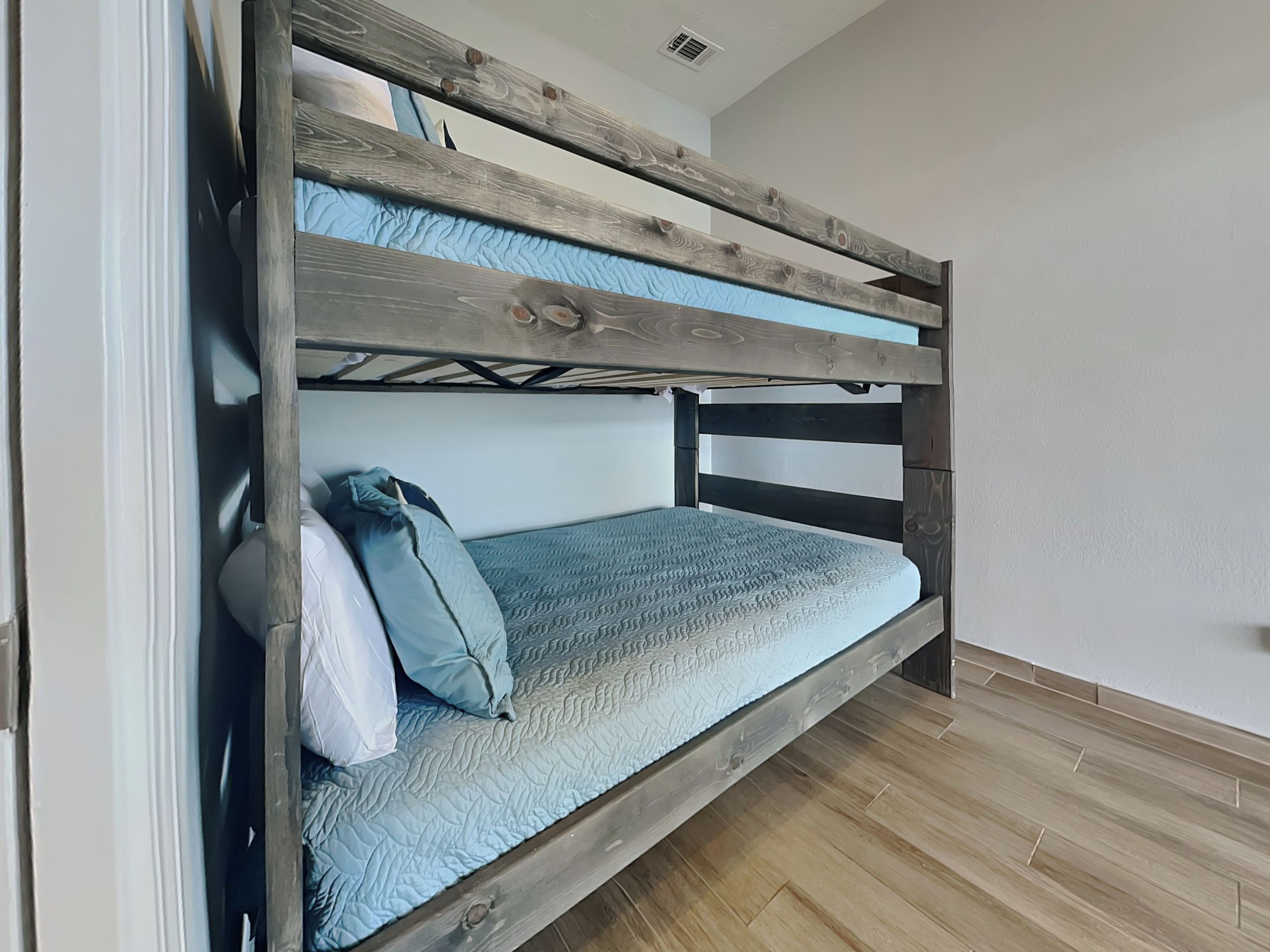 A bunk bed with a wooden frame and a blue mattress.