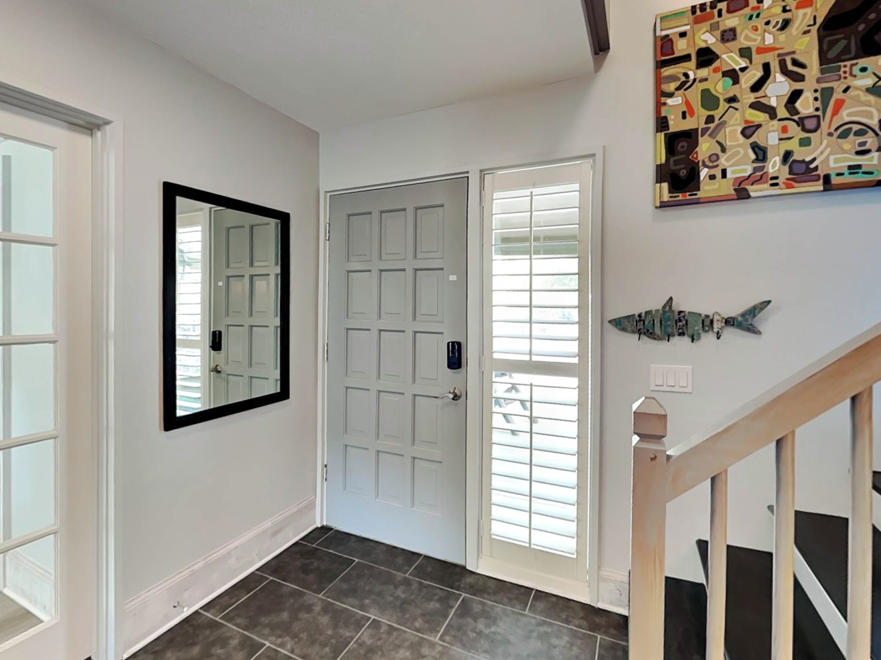 A hallway with a white door, a mirror, and a fish decoration on the wall.