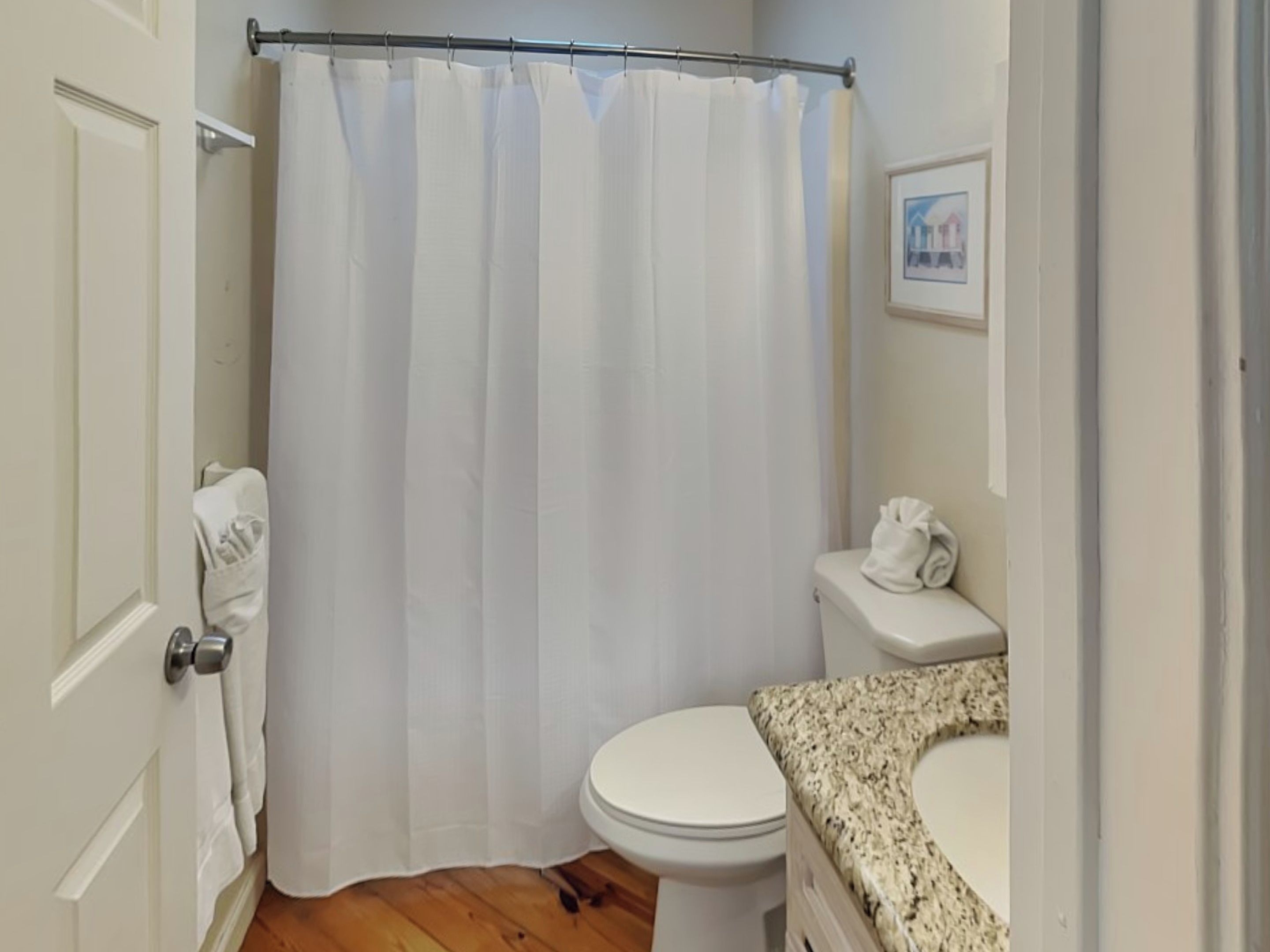 A bathroom with a shower curtain, toilet, and sink.