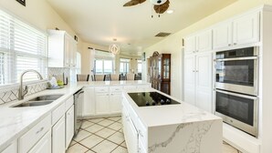 A spacious kitchen with white cabinetry, a central island, and built-in ovens.
