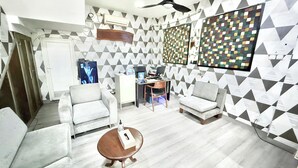 Una sala de estar moderna con un sofá, sillones, una mesa baja y un escritorio con una computadora.