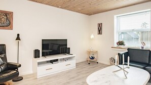 A modern living room with a flat-screen TV, leather furniture, a white coffee table, and a window with blinds. - 6 Person Holiday Home in Gedser (Gedser)