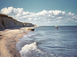 A coastal beach with cliffs, calm sea, and clear sky. - 6 Person Holiday Home in Gedser (Gedser)