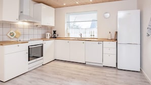 A modern kitchen with white cabinetry, a wooden countertop, a built-in oven, and a refrigerator. - 6 Person Holiday Home in Gedser (Gedser)