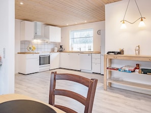 A modern kitchen with white cabinets, a wooden countertop, a built-in oven, and a window with blinds. - 6 Person Holiday Home in Gedser (Gedser)