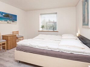A bedroom with a bed, a window with blinds, a chair, a small table, and a painting on the wall. - 6 Person Holiday Home in Gedser (Gedser)