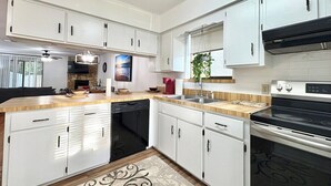 A modern kitchen with white cabinetry, a dishwasher, a stove, and a sink. - Charming 2-bedroom townhome with AC, WiFi in lovely Jacksonville (Jacksonville)