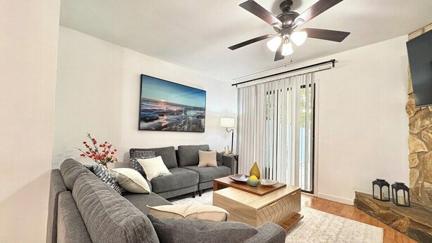 A modern living room with a grey sofa, a coffee table, a fireplace, and a ceiling fan. - Charming 2-bedroom townhome with AC, WiFi in lovely Jacksonville (Jacksonville)