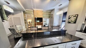 Una cocina moderna con encimera de granito negro, armarios blancos y un comedor con una mesa redonda y sillas.