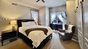 Habitación de hotel con una cama, una silla, un escritorio y un televisor.