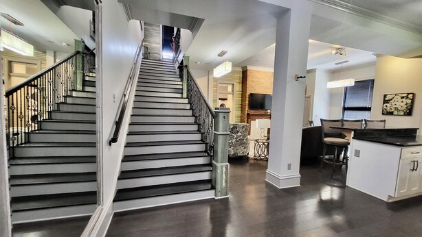 Un interior moderno con una escalera que conduce a un segundo piso, una zona de cocina con una mesa de comedor y un espacio de estar con un sofá.