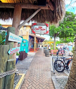 A pathway leading to a building with a sign reading 'The Cottage.' There are outdoor seating areas and a bicycle parked by the entrance. - Newly Updated, Walk to Siesta Key Beach, Tennis, Heated Pool (Siesta Key)