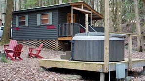 Eine Holzhütte mit Whirlpool und zwei Adirondack-Stühlen davor.