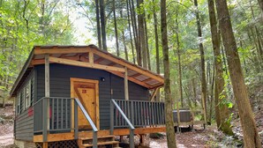 Eine Holzhütte mit einer Holzterrasse, einer Treppe und einer Tür mit der Aufschrift "2B".