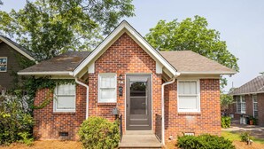 A single-story brick house with a front door, two windows, and a small porch.