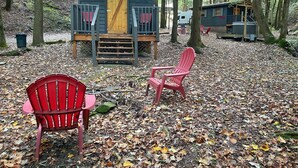 Una cabaña con un porche, dos sillas Adirondack rojas y una terraza cubierta.