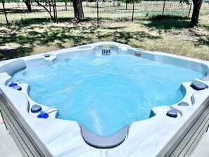 Ein Whirlpool mit Düsen, umgeben von einer grünen Fläche mit Bäumen.