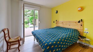 Une chambre avec un lit, une chaise, une fenêtre et une porte donnant sur un espace extérieur.
