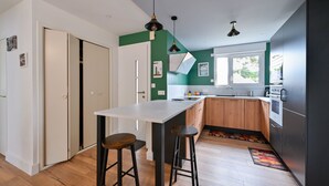 Une cuisine moderne avec un îlot central blanc, des armoires en bois et un réfrigérateur noir.