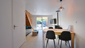 Un espacio habitable moderno con comedor, televisor y una escalera que da a una zona exterior.