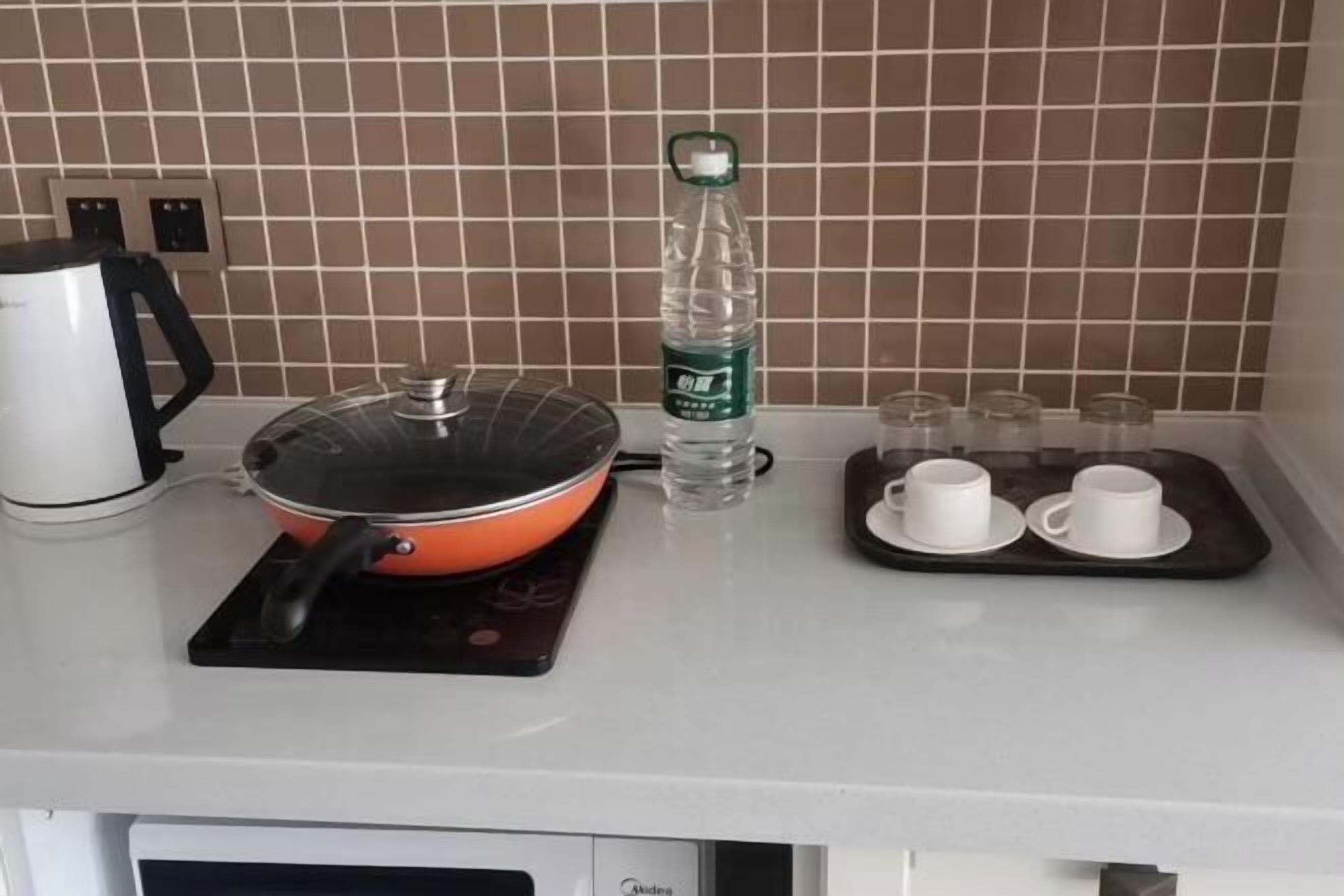 A kitchen with a stove, kettle, water bottle, and a tray with cups.