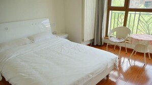 Une chambre à coucher avec un grand lit, une table de chevet, une chaise, une petite table et une fenêtre donnant sur un beau paysage.