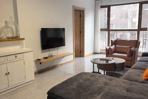 Una sala de estar moderna con un televisor de pantalla plana, un sillón de cuero, un sofá y una pequeña mesa de centro.
