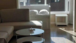 Un salon moderne avec un canapé, une table basse ronde et un lit avec des coussins.