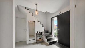 Eine moderne Treppe mit schwarzer Geländer, einer hängenden Leuchte und einem kleinen Konsolentisch mit Pflanze.