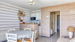 Un espacio habitable compacto con área de cocina, mesa de comedor y sofá.