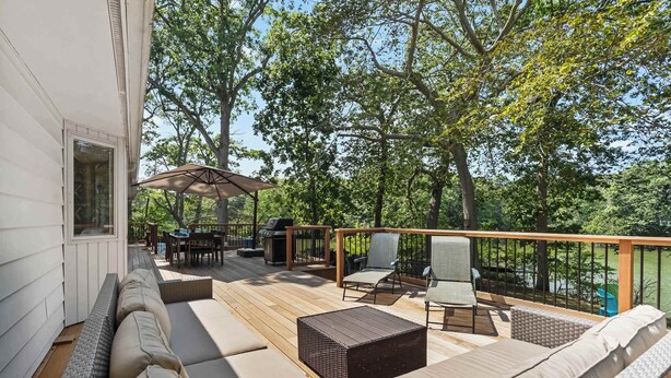 A deck with outdoor furniture, including sofas and chairs, and a table with chairs. - Waterfront Hot Tub Retreat w Kayaks | Kayak Point (North Fork)