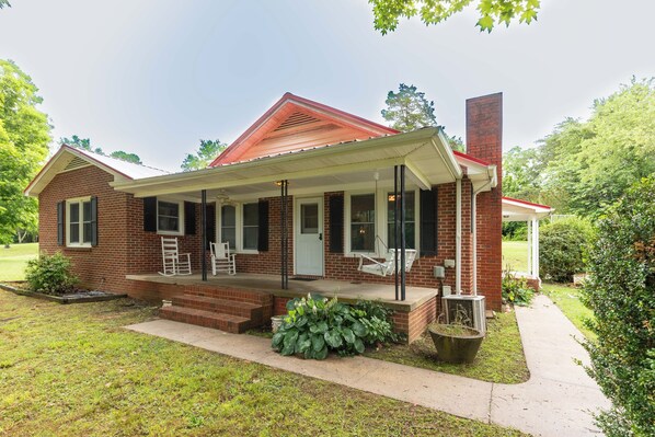 A brick house with a porch, a chimney, and a small garden. - Red Robin Retreat - Near Lake James, NC (Morganton)