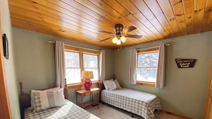 A room with two beds, a ceiling fan, a desk with a lamp, and a sign indicating the location is White Mountain National Forest. - Mountain View Escape - Stunning Views! Bethlehem, NH Cabin Near Skiing & Hiking (Bethlehem)