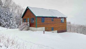 A wooden cabin with a metal roof, a front porch, and a staircase leading to the entrance. - Mountain View Escape - Stunning Views! Bethlehem, NH Cabin Near Skiing & Hiking (Bethlehem)