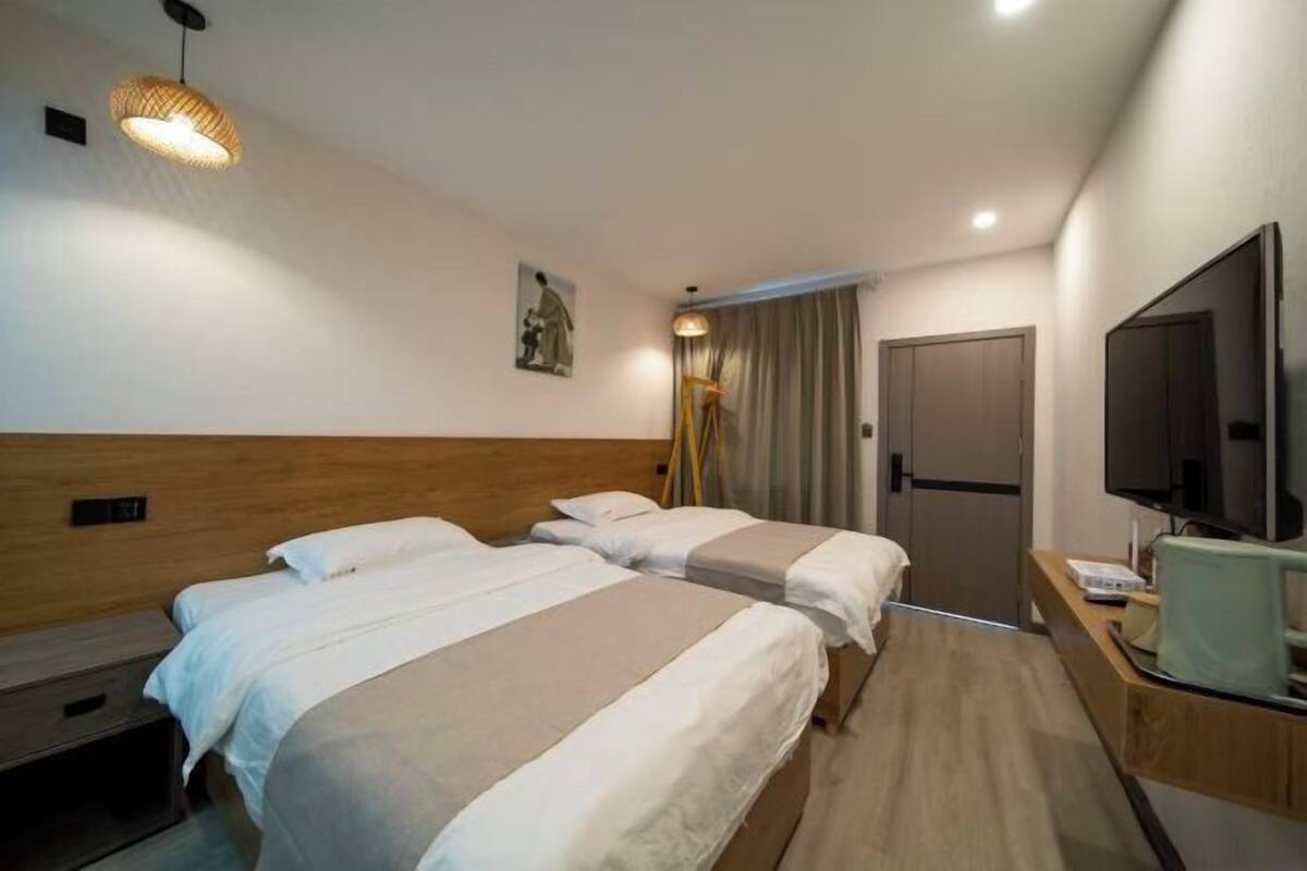 Una habitación de hotel con dos camas, televisión, escritorio y un cuadro en la pared.