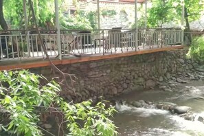 Eine Steinkonstruktion überspannt einen Fluss, mit Metallgeländer und einem hölzernen Gehweg.